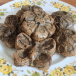 A plate of little cakes in fun shapes. The muffins are a brown-green color. The plate has yellow flowers.